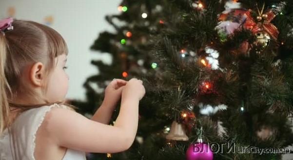 маленькая девочка украшает новогоднюю елку